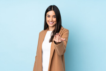 Young caucasian woman isolated on blue background inviting to come with hand. Happy that you came