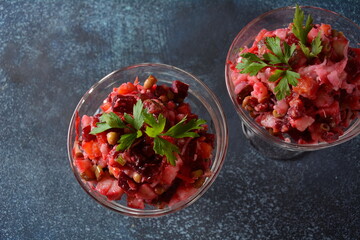 Vinegret or vinaigrette. Traditional Russian red salad with cooked and pickled vegetables, peas, beetroot, in two glass bowls on grey background.
 Vegan healthy dietary food
