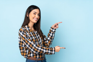 Young caucasian woman isolated on blue background pointing finger to the side and presenting a...