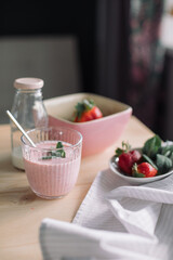 Healthy dessert with mint, fresh strawberries, glass bottle of milk on kitchen counter.
