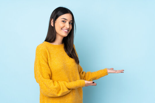Young caucasian woman isolated on blue background extending hands to the side for inviting to come