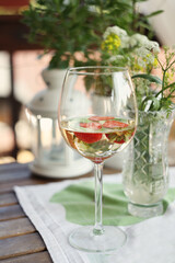 White summer wine with red ripe strawberries inside on background with wild flowers bouquet. Lifestyle photo with cozy home atmosphere.  Celebrating concept. 