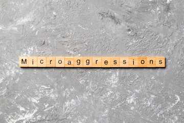 Microaggressions word written on wood block. Microaggressions text on cement table for your desing,...
