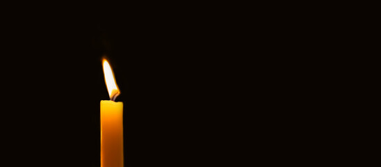 Wax candle burning in darkness. Long banner with copy space
