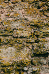 An old medieval stone wall, grass and moss on it. Wallpaper, natural background, copy space, soft focus.