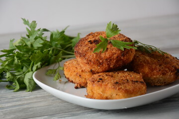 Juicy fried homemade chicken cutlets. Coated with breadcrumbs, delicious, in white dish with herbs. On old wooden background, rustic style