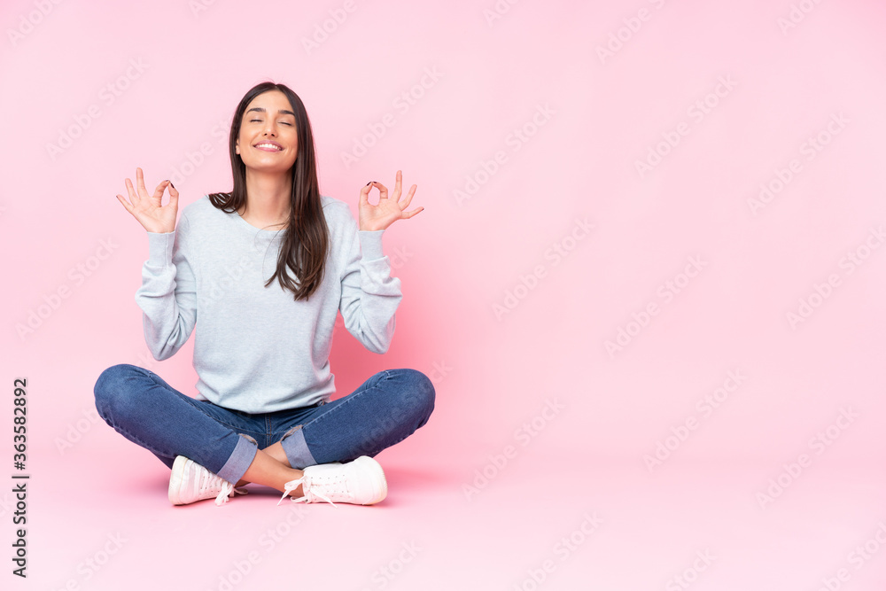 Wall mural young caucasian woman isolated on pink background in zen pose