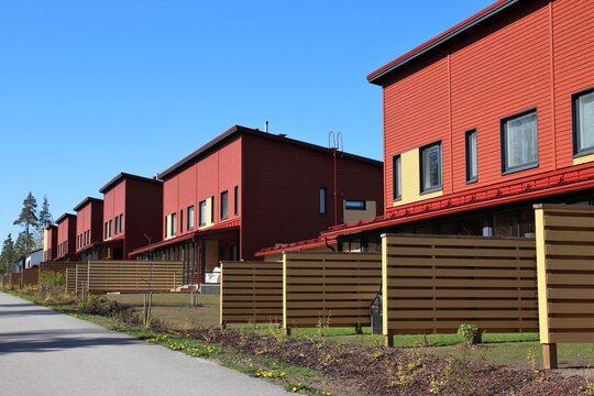 Cozy red row houses with small gardens in a suburb. Wooden fences between the neighbours provide some privacy. Scandinavian architecture. The photo is taken in Vantaa, Finland. Selective focus.
