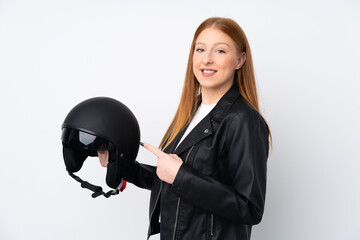 Young redhead woman with a motorcycle helmet over isolated white background and pointing it