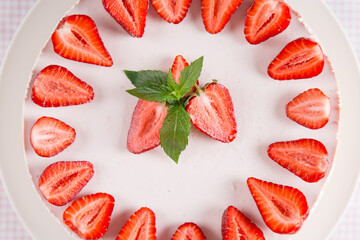 Cheesecake with strawberries and mint, on a table with a light tablecloth. Sweet homemade breakfast. Copy space.