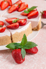 Sweet breakfast, delicious cheesecake with fresh strawberries and mint, homemade recipe without baking, on a pink stone table. Copy space.