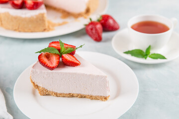 Sweet breakfast, tea and delicious cheesecake with fresh strawberries and mint, homemade recipe without baking, on a blue stone table. Copy space.