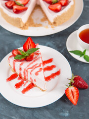 Sweet breakfast, tea and delicious cheesecake with fresh strawberries and mint, homemade recipe without baking, on dark blue stone table. Copy space.