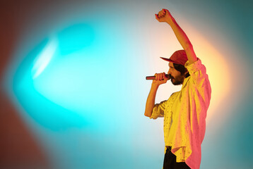 Motion. Young inspired and expressive musician, singer performing on gradient colored background in neon light. Concept of music, hobby, festival, art. Joyful artist, colorful, bright portrait.