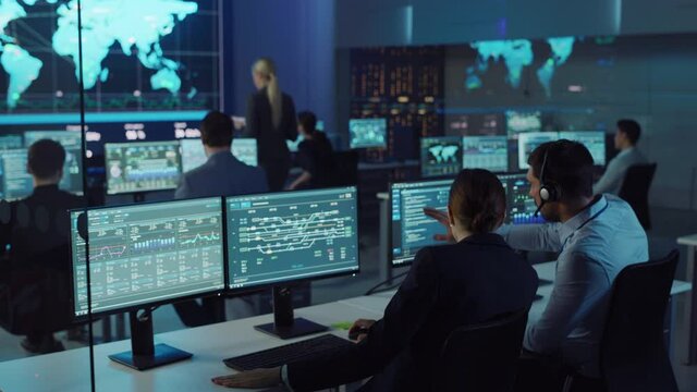 Team of Professional Computer Data Science Engineers Work on Desktops with Screens Showing Charts, Graphs, Infographics, Technical Business Data and Statistics. Low Key Control and Monitoring Room.