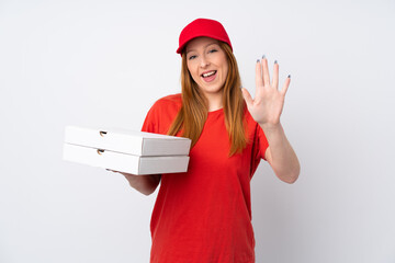 Pizza delivery woman holding a pizza over isolated pink wall saluting with hand with happy expression