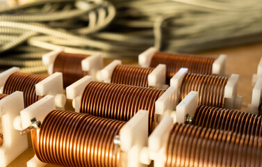 Close-up of high-frequency powerful copper wire on background of numerous blurry cables. Concept production of super modern high-tech components for transceiver appliances