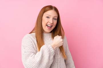 Young redhead woman over isolated pink background celebrating a victory