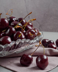 cherries in a crystal vase and on the table on a gray background