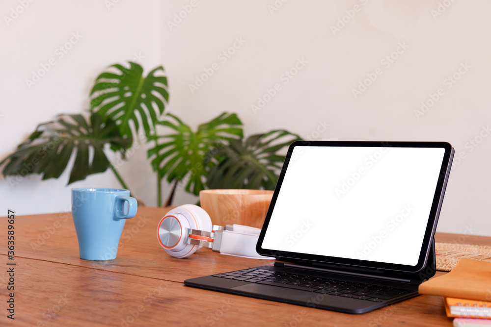 Wall mural blank screen modern laptop computer with plant pot ,headphones and notebook on wood table in office 