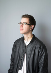Fototapeta premium Portrait of young man with glasses looking to the side with earphones