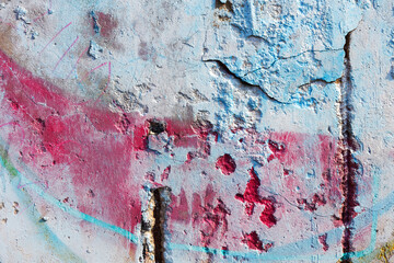 Hooligan smeared paint the walls of the old building. Landscape style. Grungy concrete surface with cracks, scratches and streaks of paint. Great background or texture.