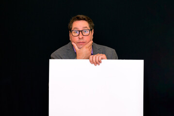 Front view image of caucasian Business man thinks something holding a blank banner isolated on black background