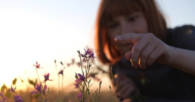 Young redhead woman in beautiful boho dress relaxing in the field during foggy sunset, female outdoors with bouquet in hands