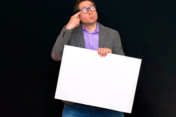 Front view image of caucasian Business man thinks something holding a blank banner isolated on black background