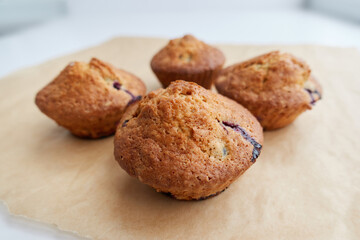 Muffins with berries on craft brown paper, close-up photo. Perfect tasty cupcakes for breakfasts, snacks, lunch or teatime. Homemade cooking and baking concept.