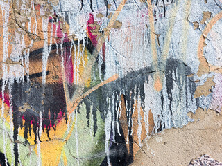 Hooligan smeared paint the walls of the old building. Landscape style. Grungy concrete surface with cracks, scratches and streaks of paint. Great background or texture.
