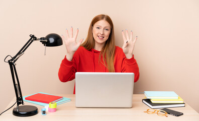 Young student woman in a workplace with a laptop counting nine with fingers