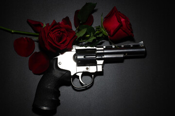 Gun and red rose on dark background