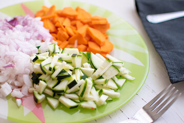Some carrots, onions and zucchini on a plate ready for a vegetable meal. Vegetarian diet concept with empty copy space for Editor's text.