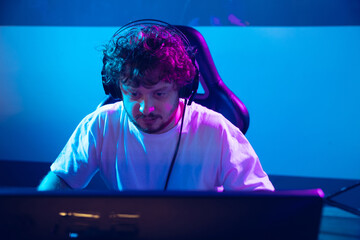 Cyber sport. Fully concentrated professional cybersport gamer playing important match. Caucasian male model practicing, training before tournament alone in neon light. E-sport, gamer, streamer. © master1305