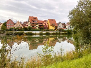 Naklejka na ściany i meble Auf der gegenüberliegenden Uferseite sieht man eine bunte Häuserfront, die sich im Fluss spiegelt