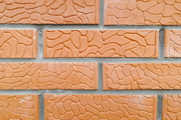 Brick wall of ceramic red brick. Orange and textured stone. Front view