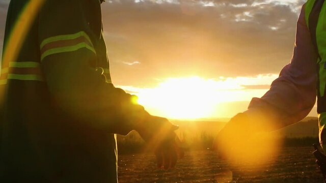 Sugar Cane Refinery / Plant. Beautiful handshake image of two people with beautiful sunset in the background - Agribusiness.