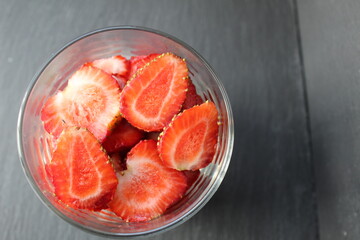 healthy delicious summer Breakfast snack in a glass fruit berries with a piece of strawberry in a glass on a gray stone black background with a place to insert text