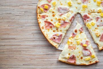 Sliced slice of hawaiian pizza on a wooden background top view with copy space
