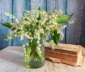 Still life with a bouquet of freshly cut lilies of the valley and a book. Spring flowers.