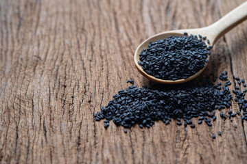 Close-up of Organic natural black sesame seeds in a wooden spoon on wood table background. 