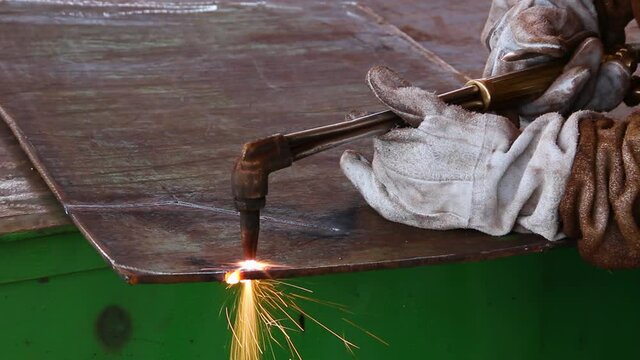 Plant / close-up of man equipped using a welding machine, iron plate welding rework, industrial maintenance