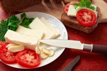 healthy food - fresh bread and feta cheese on a wooden background, tomatoes, greens and vegetables