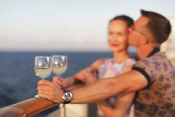 male and female hand hold glasses with white wine on a cruise liner against the sunset