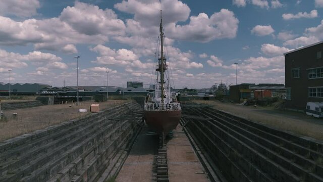 aerial shot from inside a drydock depicting an old abandoned lightboat that used to sail the Northsea. Reveal a docknear the city center of Antwerp. Gentrification in progress. Inspire2 4K prores X7