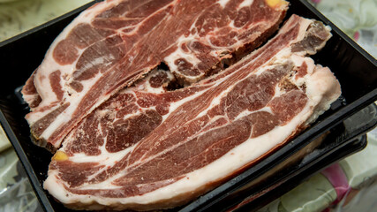 Close up detail view of raw beef lamb meat steak in a black tray packaging at the kitchen. Selective focus on foregrounds.