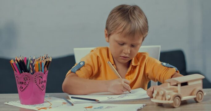 cute boy holding color pencil and drawing at home