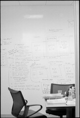 Desk and chairs against strategy on whiteboard in office