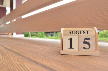 August 15, Number cube with wooden balcony background.